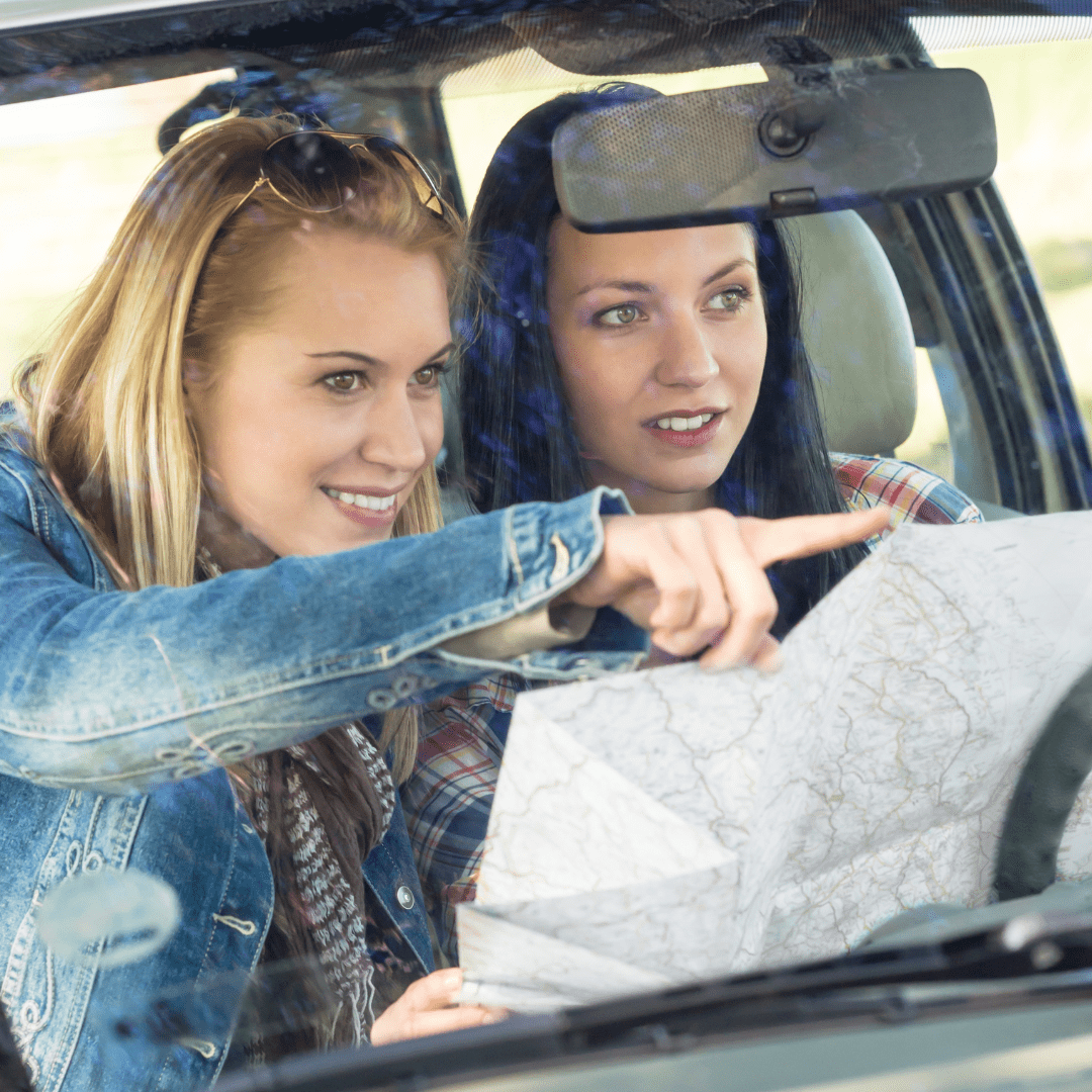 two people sitting in a car looking at a map on a road trip