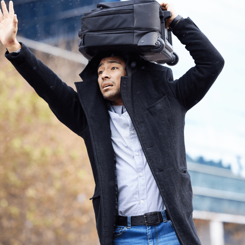 a person trying to get the attention of their ride sharing driver in the rain while trying to stay dry by using his suitcase on his head