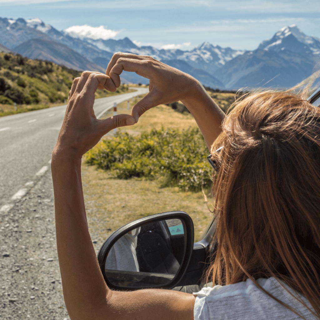 person on a road trip making heart hands