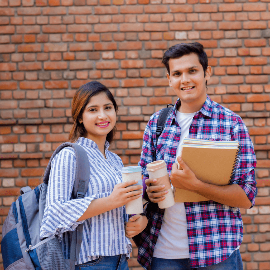 two college students smiling and holding notebooks, coffee cups and backpacks representing another year back at college