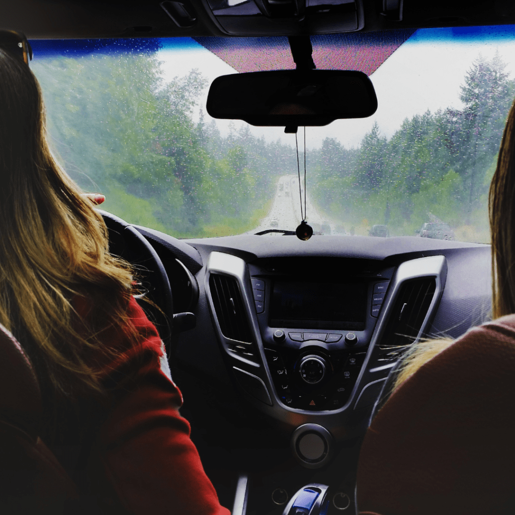 image of two people in a rental car enjoying a rainy labor day weekend drive through the woods