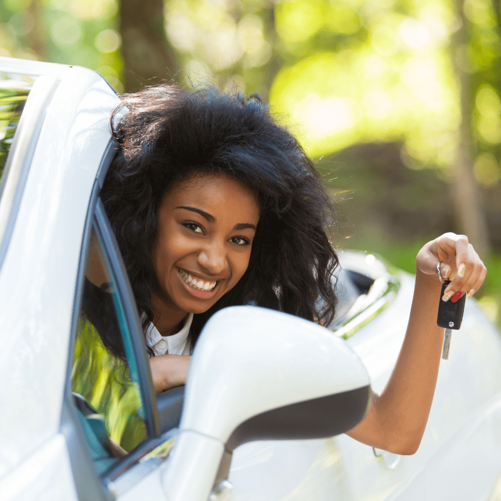 a young woman under 25 smiling while holding keys to a rental car