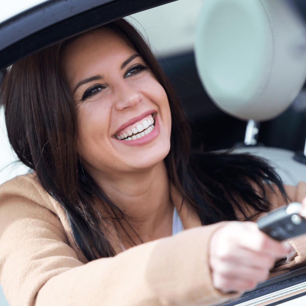 A person smiling while receiving a car key from another person representing the concept of someone renting a car for someone else