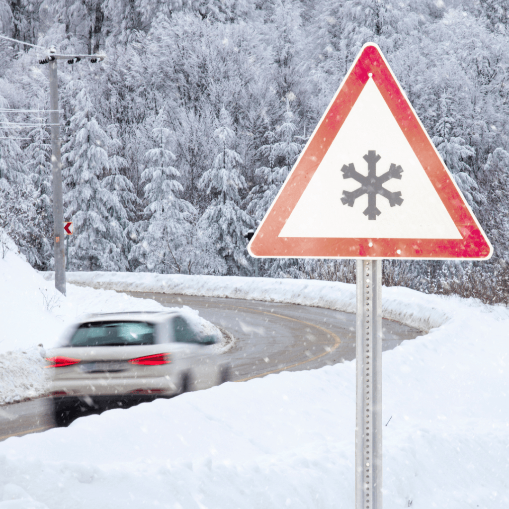 a car driving in winter near a snowflake warning sign representing winter driving safety