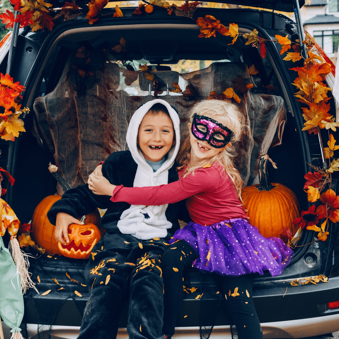 two kids in halloween masks sitting in the back of a car representing going on a Halloween Road Trip