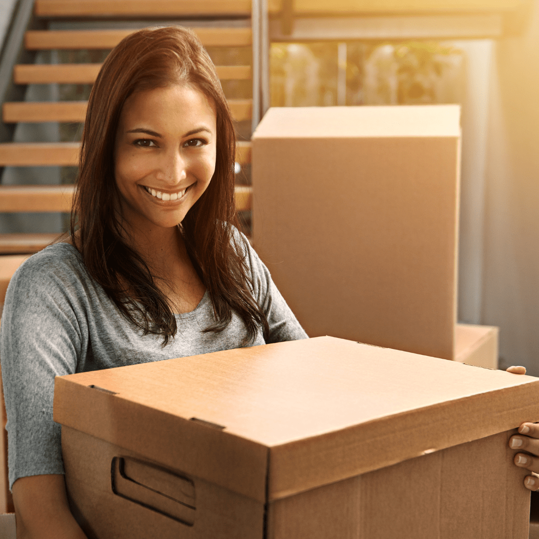 person smiling and holding a moving box