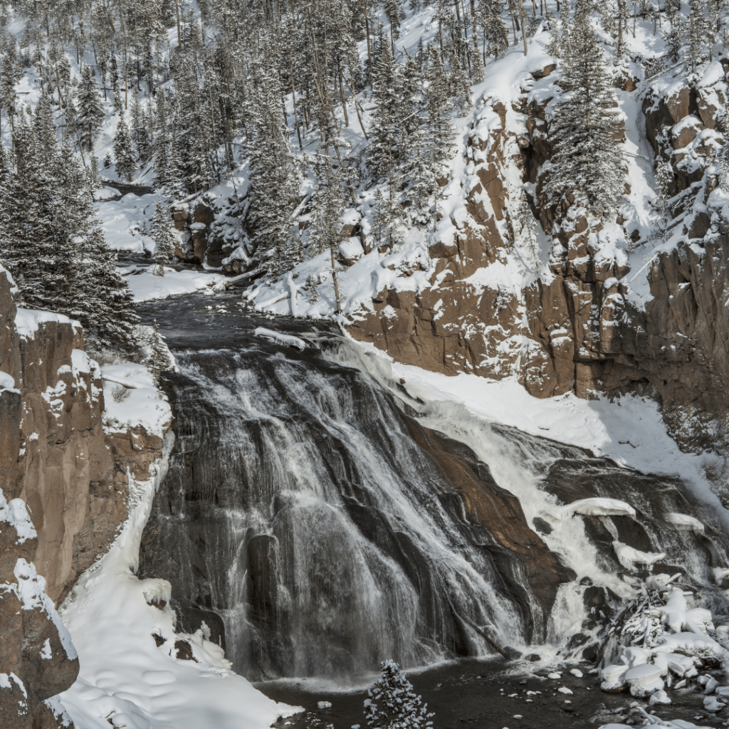 a frozen waterfall in Yellowstone national park in winter representing the top winter road trip destinations