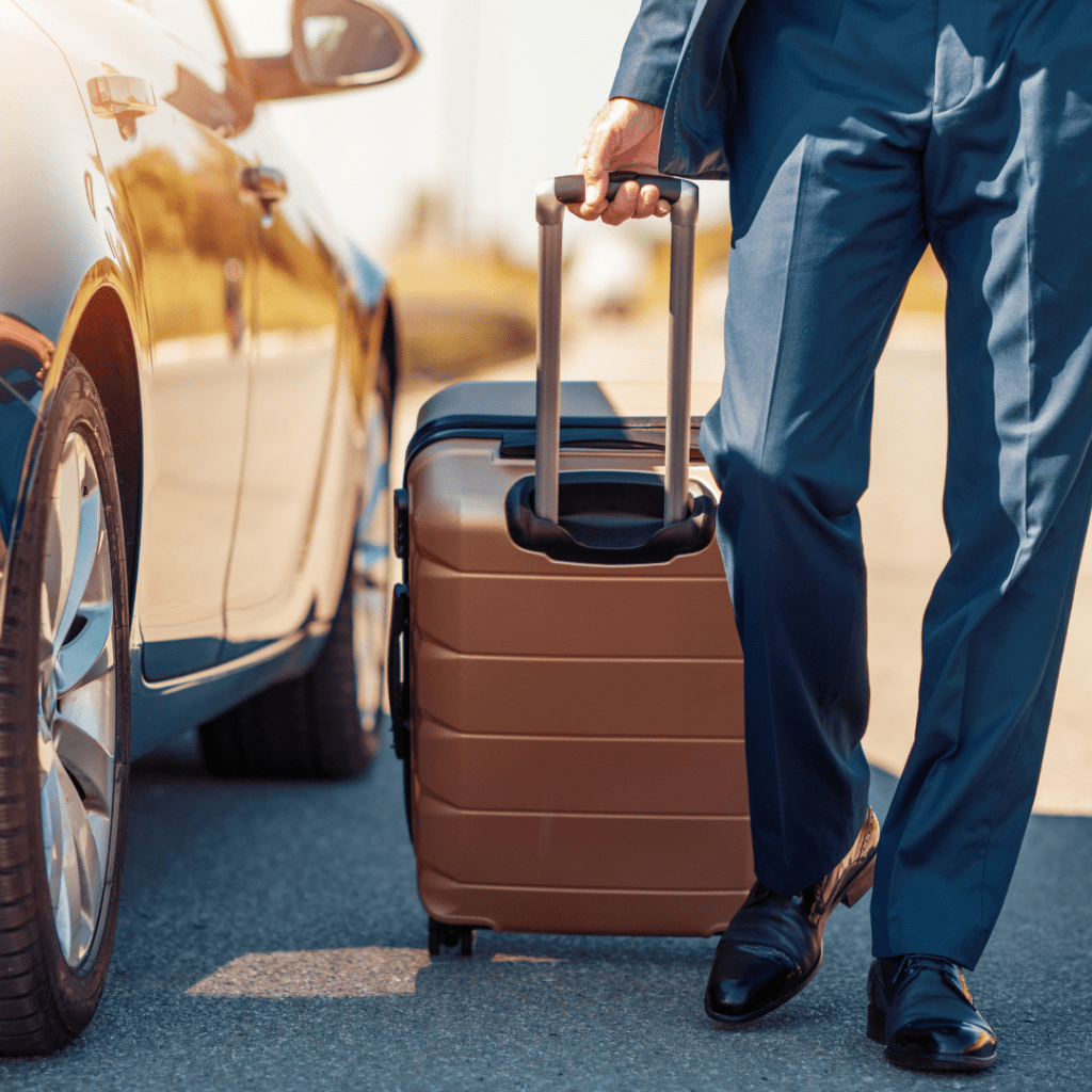 a person with a suitcase next to a car representing business travel