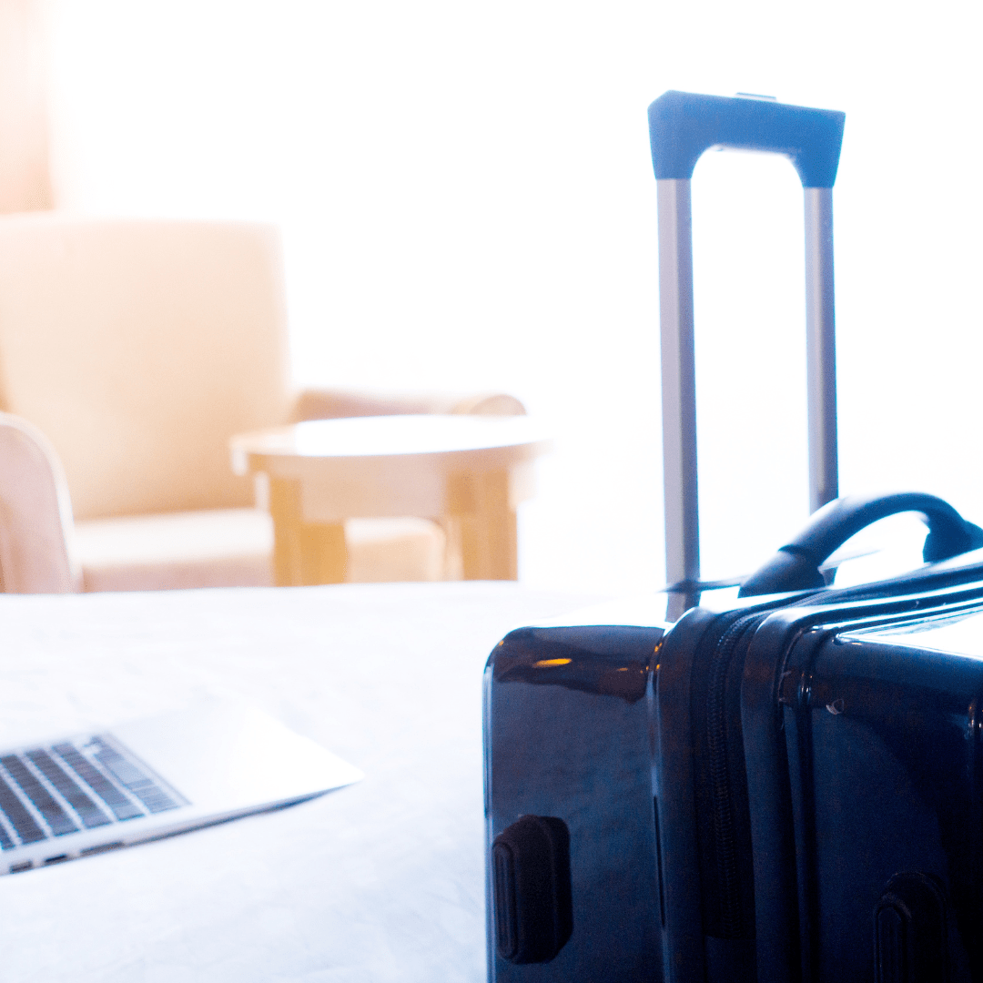 a suitcase, a desk and a laptop representing business travel