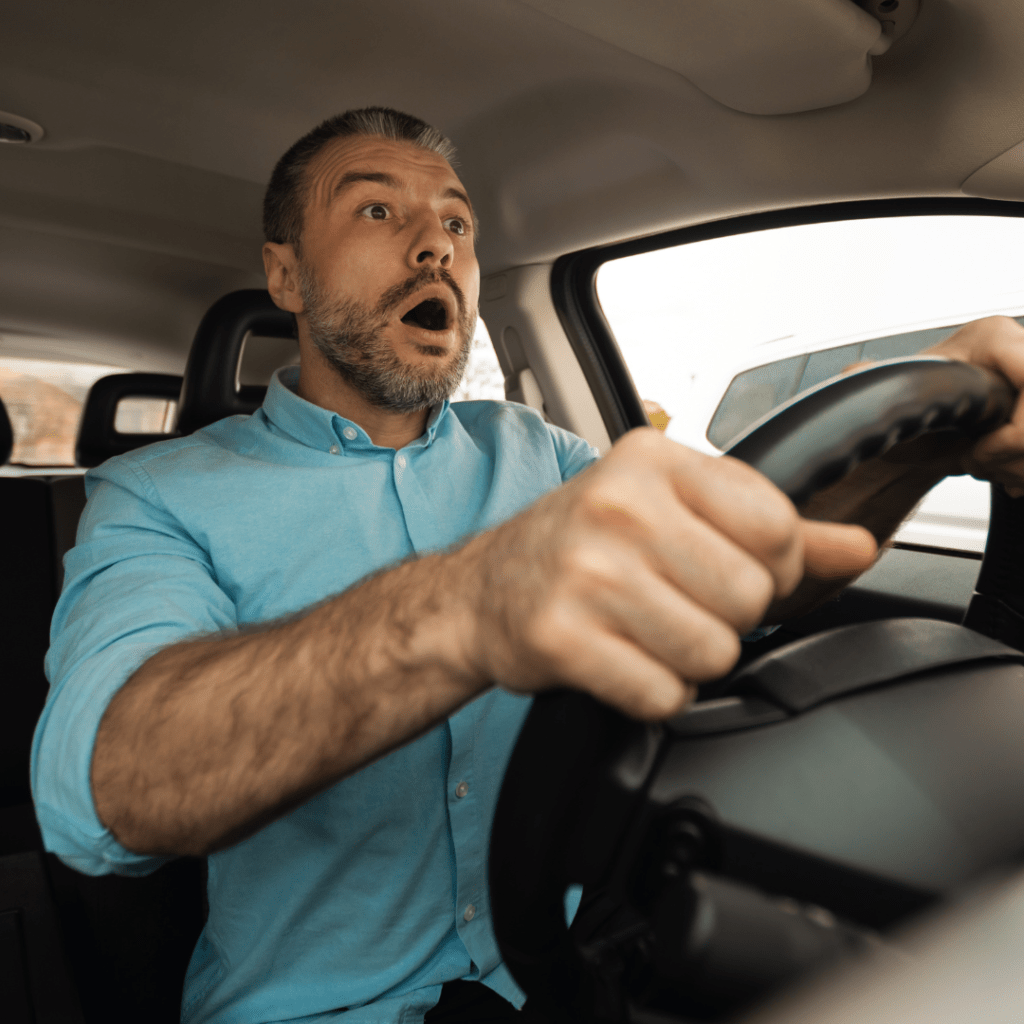 a surprised man at the wheel of a car