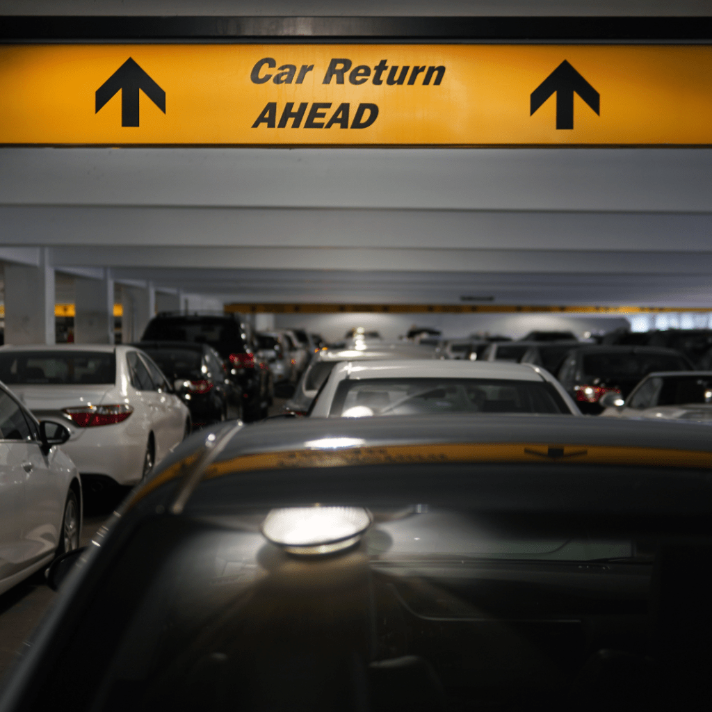 A car rental return sign in a garage indicating how to return a rental car