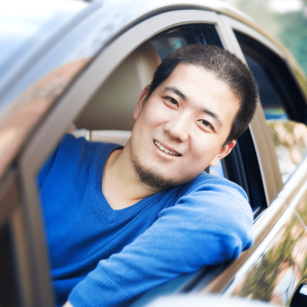 Asian man in a car  representing renting a car in the U.S.